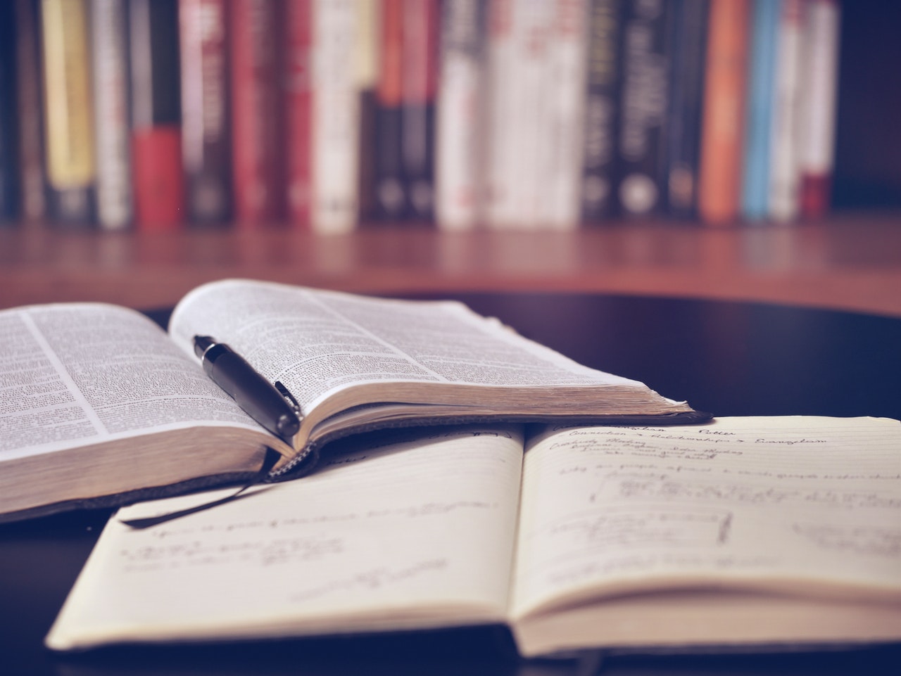 Open books on a desk with library shelf in the background
